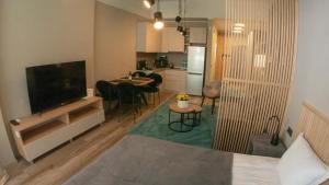 ein Wohnzimmer mit einem TV und einer Küche in der Unterkunft Луксозно студио One Place in Sofia A1 - Лозенец in Sofia