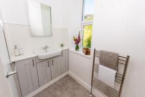 a white bathroom with a sink and a mirror at Charming coastal cottage with stunning views - Hope Cottage in Mortehoe +29 photos