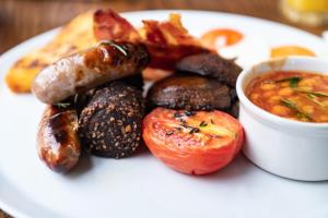 a plate of food with sausage and tomatoes and a bowl of soup at The Bear in Bath