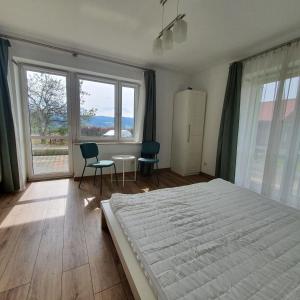 a bedroom with a bed and two chairs and windows at Apartament Tadeusz 2 B in Krynica Zdrój