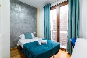 a bedroom with a bed with a blue blanket and a window at Precioso Apartamento en Granada in Granada