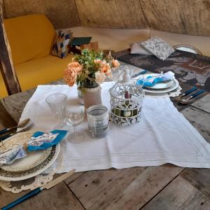 a table with a white table cloth and flowers on it at TENTE SAFARI LODGE DANS FORET LUXURIANTE in Vielle-Tursan