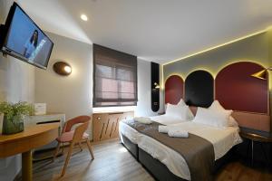 a bedroom with a bed and a desk and a tv at Hotel-Restaurant Axion in Weil am Rhein