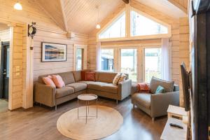 a living room with a couch and a table at Lähderinne - Beachfront 2 bedroom log cabin, private beach & sauna in Puolanka