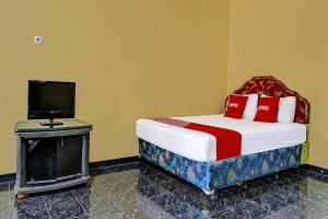 um quarto com uma cama com uma televisão e uma cama gmaxwell gmaxwell gmaxwell em SPOT ON 91798 Hotel Grand Mutiara em Cikampek