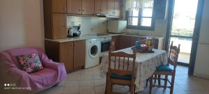 cocina con mesa y sillas y cocina con lavadora en Votsalo Beach House, en Moutsoúna