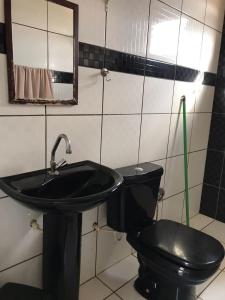 a bathroom with a black toilet and a sink at Recanto Magalhães in Barra do Garças