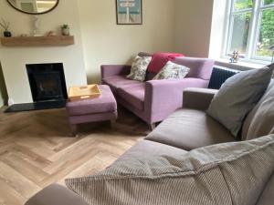 a living room with two purple couches and a fireplace at Lovely quiet cottage Sleeps 4 adults, 4 children, Dog Friendly in Cley next the Sea