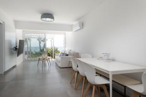 a white dining room with a white table and chairs at The MedView Garden House in Pervolia