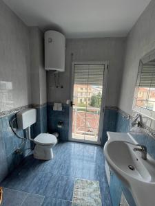 baño con aseo y lavabo y ventana en Pedestrian Street Center Apartment, en Shkodër