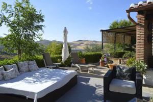 a patio with a bed and a chair and an umbrella at Fantastic Private Villa with pool near Ardales and Caminito del Rey in Ardales