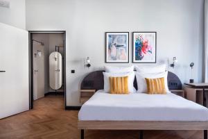 um quarto com uma grande cama branca com almofadas laranja em numa I Novela Rooms & Apartments em Berlim