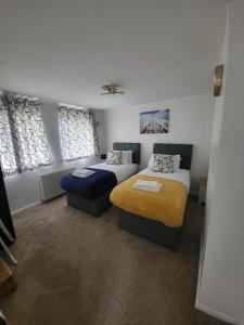 a bedroom with two beds and two windows at Spacious serviced home with free parking & Wi-Fi in Willenhall