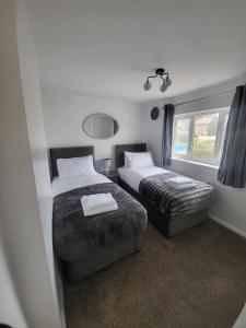 1 dormitorio con 2 camas y ventana en Spacious serviced home with free parking & Wi-Fi, en Willenhall