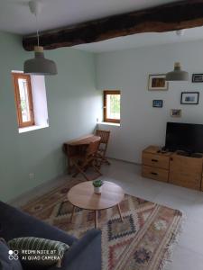 a living room with a table and a tv at Suite au pied de la montagne et vue imprenable in Saint-Alban