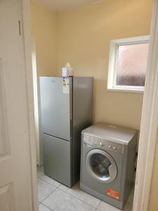 a kitchen with a refrigerator and a washing machine at Spacious serviced home with free parking & Wi-Fi in Willenhall