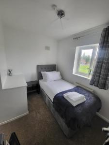 a small bedroom with a bed and a window at Spacious serviced home with free parking & Wi-Fi in Willenhall