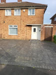 a brick house with a white door and a driveway at Spacious serviced home with free parking & Wi-Fi in Willenhall