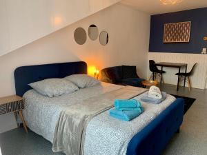 sypialnia z niebieskim łóżkiem i ręcznikami w obiekcie PYRENE HOLIDAYS Studios proches des Thermes de Bagnères-De-Bigorre et navettes ski La Mongie w mieście Bagnères-de-Bigorre
