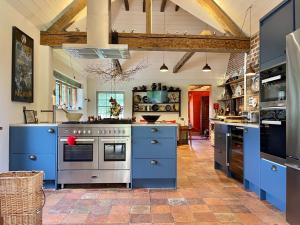 cocina grande con armarios azules y fogones en Moat Farm House en Ash