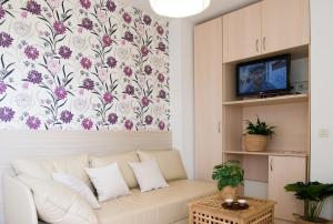 a living room with a white couch and a floral wallpaper at Apartments Sandra in Poreč
