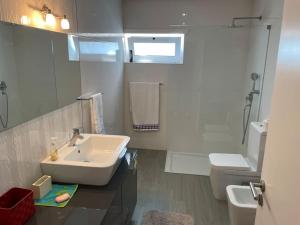 a white bathroom with a sink and a toilet at Moradia alegre no centro da Vila da Tocha. in Tocha +49 photos