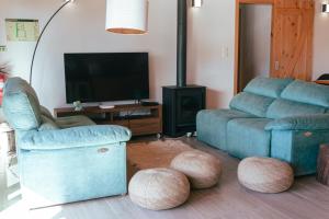 a living room with a couch and a chair and a tv at Quinta do Abacate - Glamping Park in Angra do Heroísmo