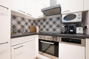 une cuisine avec des armoires blanches et un micro-ondes dans l'établissement Apartment in the central area. 5 minute's walk to the Danube., à Vienne