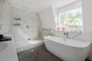 La salle de bains blanche est pourvue d'une baignoire et d'une fenêtre. dans l'établissement 1st Class Covent Garden Residences for 1st Class Guests, à Londres