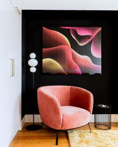 una silla rosa en una sala de estar con una pintura en 1st Class Covent Garden Residences for 1st Class Guests en Londres