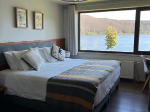 a bedroom with a bed with a view of a lake at Hotel Boutique Cutipay in Valdivia