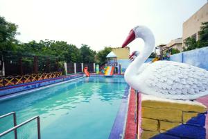 a swan statue sitting on the edge of a swimming pool at Swad Ri Dhani, Ajmer in Ajmer