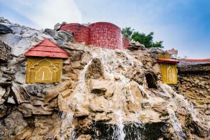 a waterfall in the middle of a mountain with houses at Swad Ri Dhani, Ajmer in Ajmer
