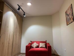 uma cadeira vermelha com duas almofadas num quarto em Americas Apartment em Sucre