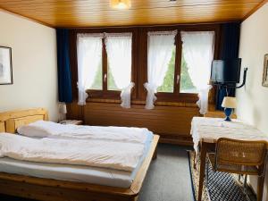 a bedroom with two beds and a table and windows at Hotel Sternen Worb in Worb