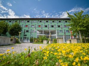 ein grünes Gebäude mit Blumen davor in der Unterkunft Kolpinghaus Salzburg in Salzburg