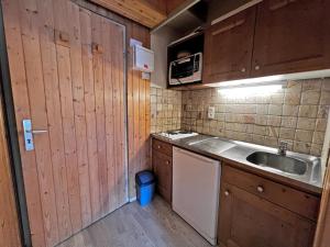 een kleine keuken met houten kasten en een wastafel bij Aiguille Verte 27 - Studio avec vue in La Clusaz