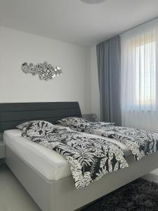 uma cama com um edredão preto e branco e uma janela em MY PLACE em Slavonski Brod