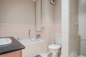 a bathroom with a toilet and a sink and a shower at Glammys @77 Grayston Drive in Johannesburg