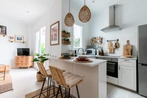 kuchnia z białymi urządzeniami i blatem ze stołkami w obiekcie Oasis con patio y encanto en centro Sevilla w Sewilli