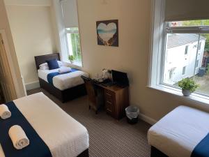 a hotel room with two beds and a desk and a window at The New Brighton Hotel in New Brighton