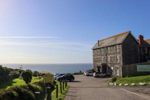 an old building with cars parked next to the ocean at Housel Bay Hotel in Lizard