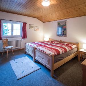 Haus Wick في Klosters Serneus: غرفة نوم بسرير ونافذة وكرسي
