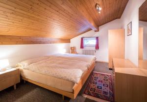 Haus Wick في Klosters Serneus: غرفة نوم بسرير كبير بسقف خشبي