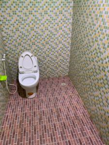 a bathroom with a toilet in a tiled room at Krua Chehe Resort ครัวเจ๊ะเห รีสอร์ท 