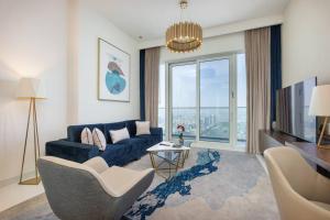 ein Wohnzimmer mit einem blauen Sofa und einem großen Fenster in der Unterkunft Exquisite Apartment Minutes Away from the Beach in Dubai