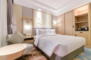 a bedroom with a large white bed and a table at Aber City Center in Hafr Al Baten