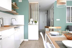 kuchnia z białymi szafkami i drewnianym stołem w obiekcie Bandol AZUR - 2 chambres, balcon, bord de mer, wifi, climatisé et parking privé w mieście Bandol