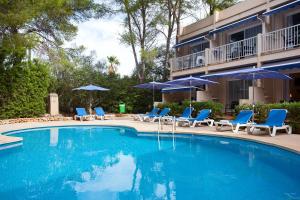 a swimming pool with blue chairs and umbrellas at Apartamentos Cala Murada Minigolf in Cala Murada