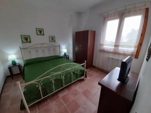 um quarto com uma cama verde e uma televisão em Il Baglio di donna Rosa em Custonaci